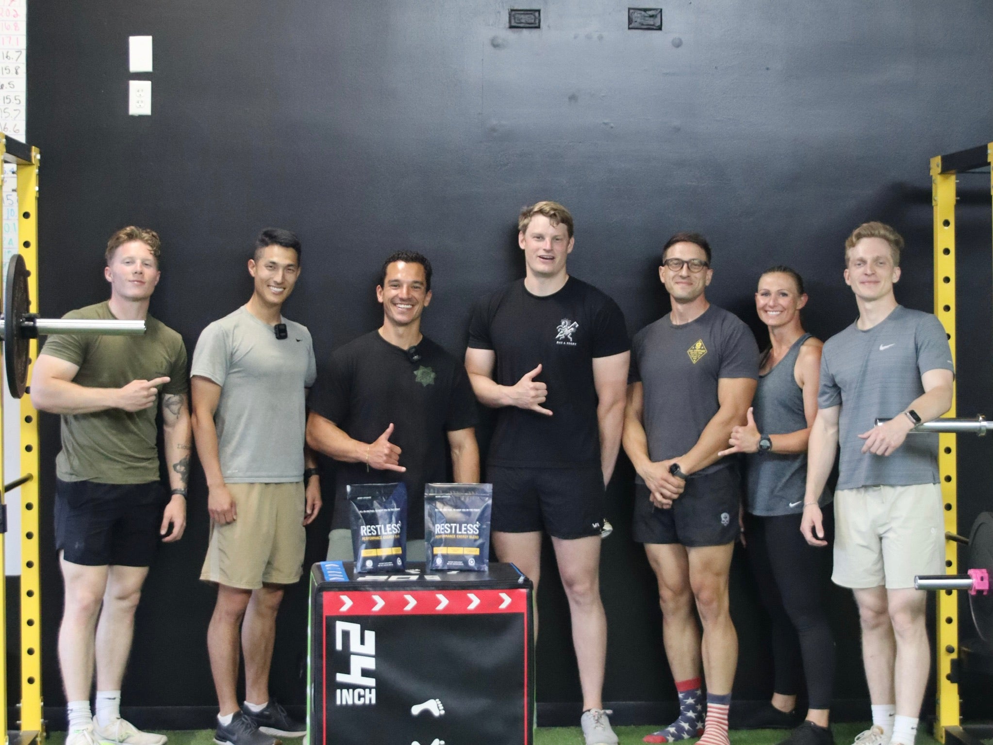 Group of athletes and military standing together in gym with Restless Performance Energy Blend on display