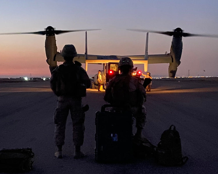 Military personnel preparing to board aircraft at sunset, carrying gear and representing the Restless community